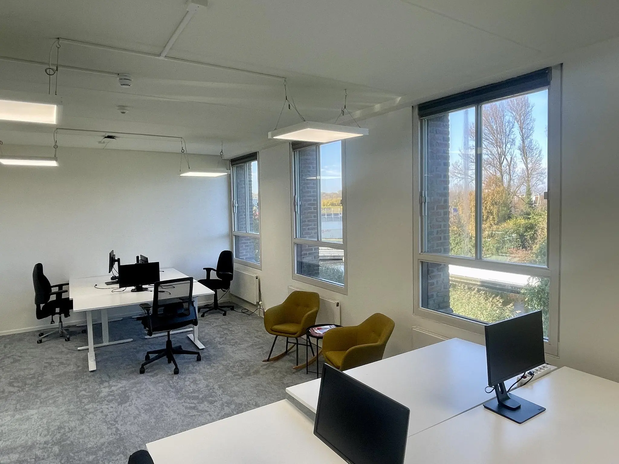 Modern kantoorpand aan de Jan Leentvaarlaan met werkplekken, bureaustoelen en grote ramen met uitzicht op groen.